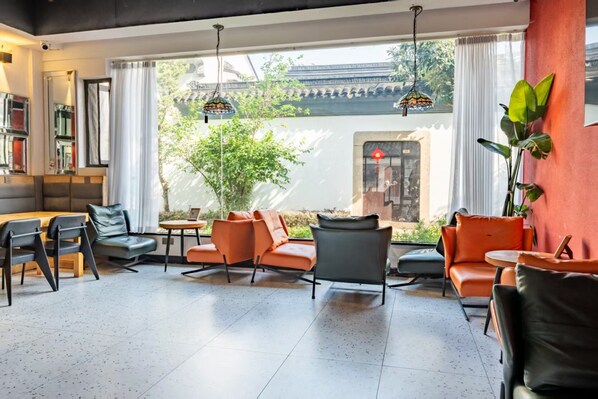 A modern hotel lobby with a seating area, large windows, and a view of traditional architecture.