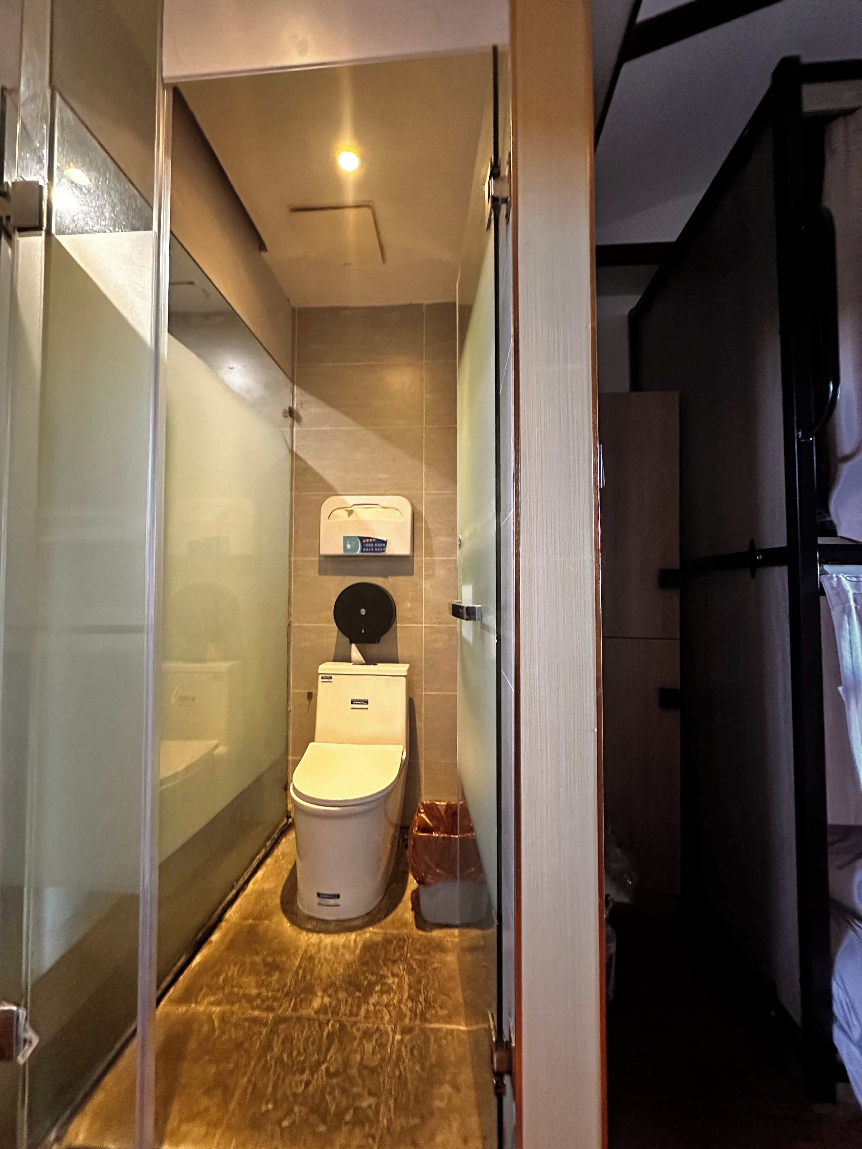 Une petite salle de bain comprenant des toilettes, un distributeur de serviettes et un espace douche.