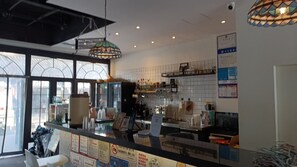 A restaurant interior with a counter, hanging lights, and large windows.