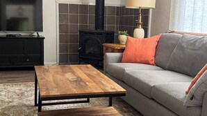 Una sala de estar con un sofá, una mesa de centro de madera, un televisor, una chimenea y una lámpara.