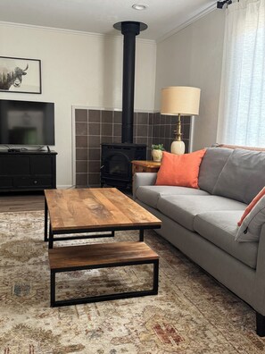 A living room with a sofa, a wooden coffee table, a TV, a fireplace, and a lamp.