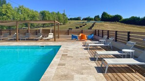 Una piscina con sillas de descanso y una terraza de madera.
