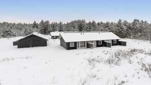 A snow-covered landscape with two modern buildings, one with a sloped roof and another with a flat roof, surrounded by a forest. - 4 Star Holiday Home in Pandrup (Pandrup)