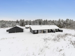 A snow-covered landscape with two modern buildings, one with a sloped roof and another with a flat roof, surrounded by a forest. - 4 Star Holiday Home in Pandrup (Pandrup)