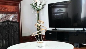 A room with a round glass table, a fireplace, a TV, and decorative wall clocks. - Spacious & Renovated 3BR/2BA Full Kitchen. Steps from McCormick Place & the Loop (Chicago)