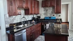 A kitchen with dark wooden cabinets, a stainless steel dishwasher, a marble backsplash, and patterned floor tiles. - Spacious & Renovated 3BR/2BA Full Kitchen. Steps from McCormick Place & the Loop (Chicago)