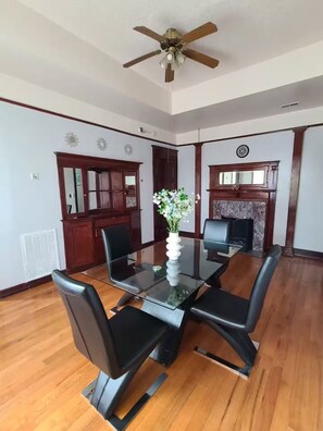 A conference room with a glass table, black chairs, wooden flooring, a ceiling fan, and a fireplace. - Spacious & Renovated 3BR/2BA Full Kitchen. Steps from McCormick Place & the Loop (Chicago)