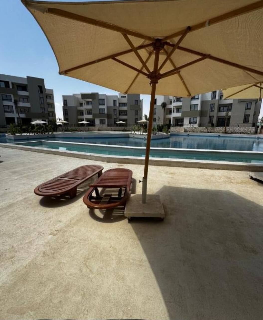 Uma área de piscina com espreguiçadeiras e um grande guarda-sol.