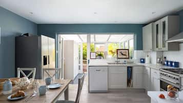 A modern kitchen with a dishwasher, stove, and a dining area with a table set for two.