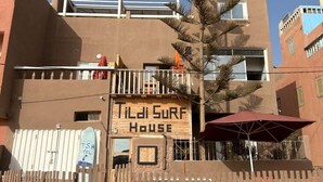 A building with a sign reading 'Tildi Surf House' and a wooden fence in front. - Tildi Surf House (Imsouane)