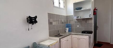 A compact kitchen with white cabinets, a blue sofa, and a tiled backsplash.