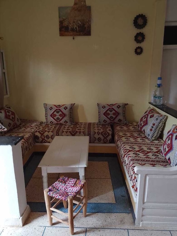 A living room with a sofa set, a small table, and a wooden stool.