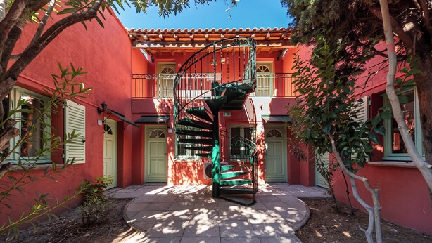 Un edificio rojo con una escalera en espiral que lleva a un balcón.