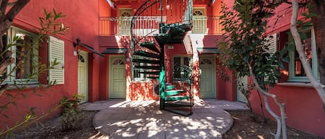 A red building with a spiral staircase leading to a balcony.