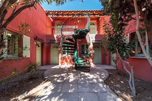 A red building with a spiral staircase leading to a balcony. - Le Patio des Papes (Avignon)