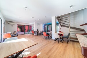 Un interior moderno con una escalera, varias mesas y sillas.