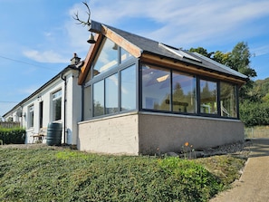 A modern building with large windows, a sloped roof, and a bell on the roof. - Cosy Cottage close to Munros and Cycle path in Lochearnhead  (Lochearnhead)