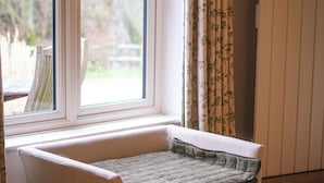 A room with a window, a cushioned bench, and a radiator. - Broomhill Cottage (Petworth)