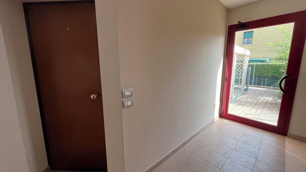 A hallway with a brown door, a red-framed glass door, and a tiled floor. - Martina's House (Villanova di Camposampiero)
