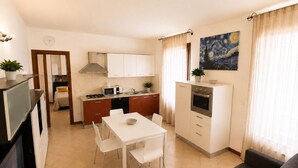 A compact living space with a kitchenette, dining area, and a sofa. - Martina's House (Villanova di Camposampiero)