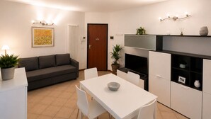 A compact living space with a sofa, dining table, and kitchenette. - Martina's House (Villanova di Camposampiero)