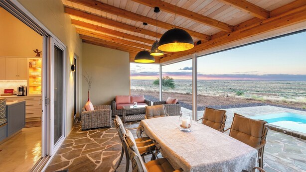 Un patio amplio con mesa de comedor, mobiliario de mimbre y vistas a un paisaje desértico.
