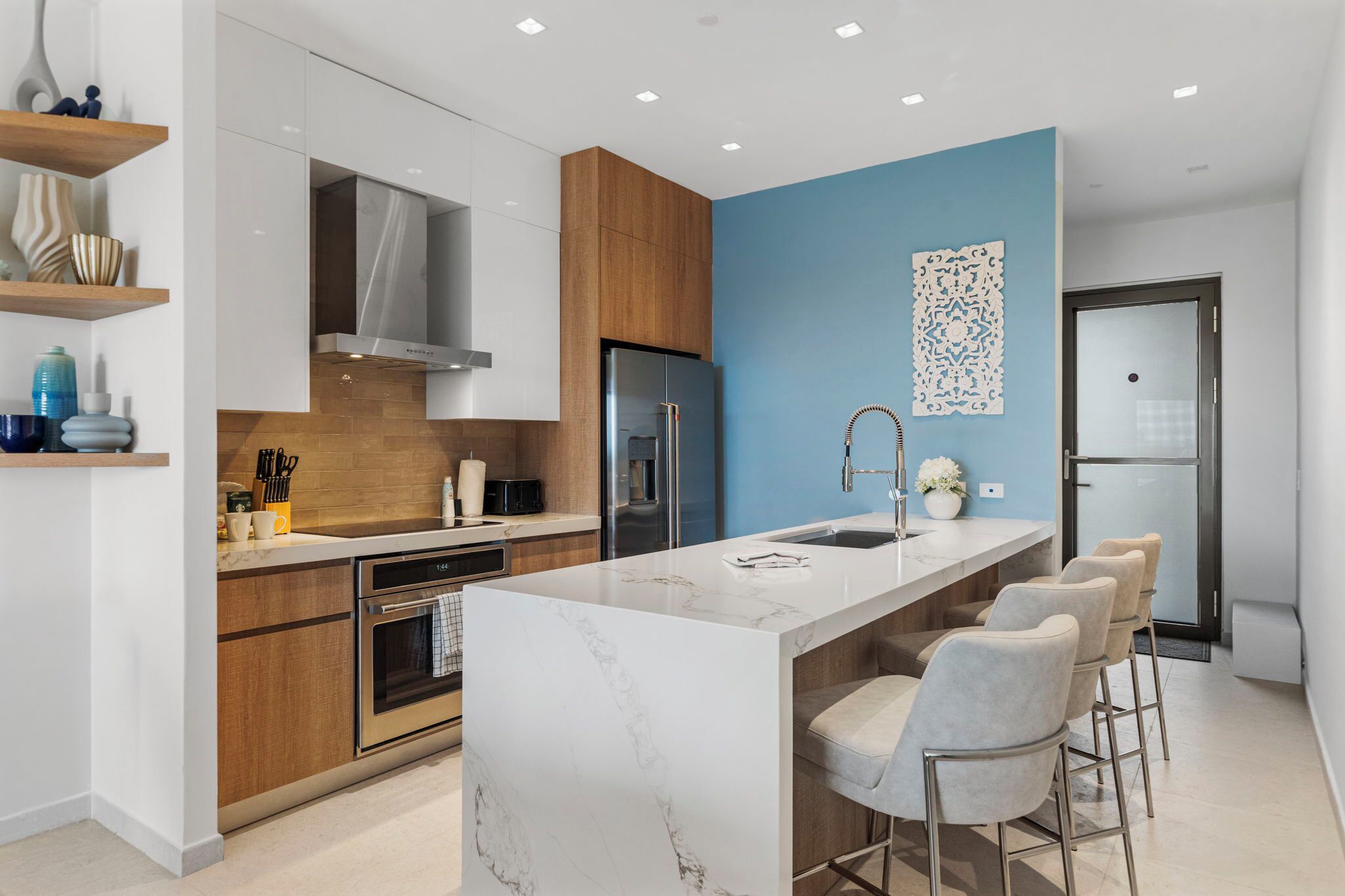 Una cocina moderna con una isla de mármol, electrodomésticos de acero inoxidable y una pared de acento azul.