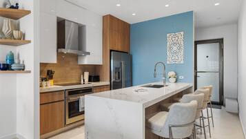 Una cocina moderna con una isla de mármol, electrodomésticos de acero inoxidable y una pared de acento azul.