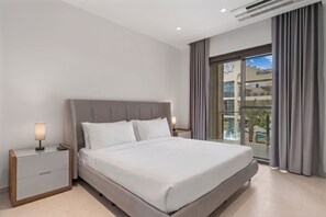 A modern hotel room with a large bed, two bedside tables, a nightstand, and a view of a pool through a glass door. - Walishali 215 (Oranjestad)