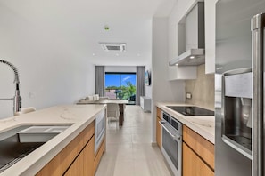 Eine moderne Küche mit Einbauofen, einem Edelstahl-Kühlschrank und einem Fenster mit Blick auf einen Balkon.