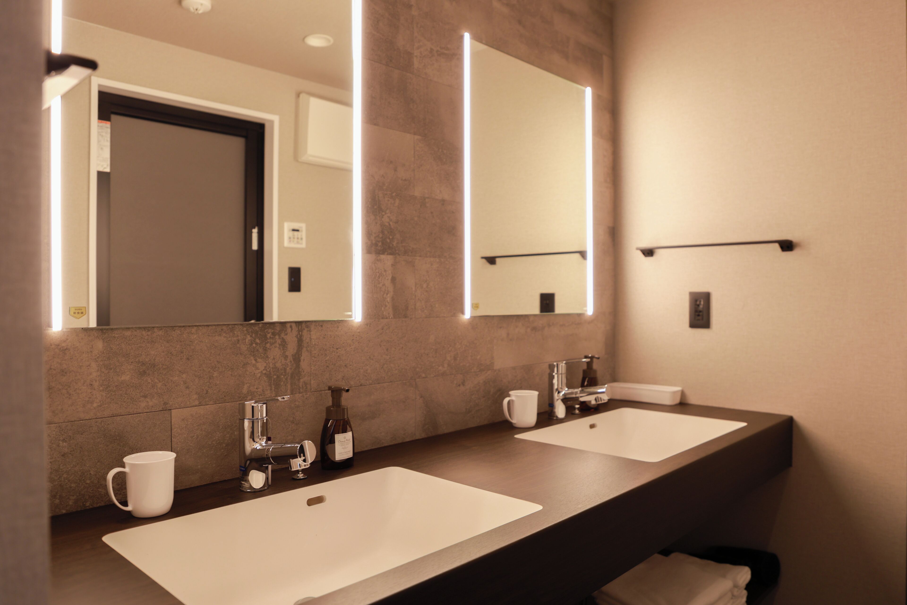 A modern bathroom with two sinks, a mirror, and a towel rack.