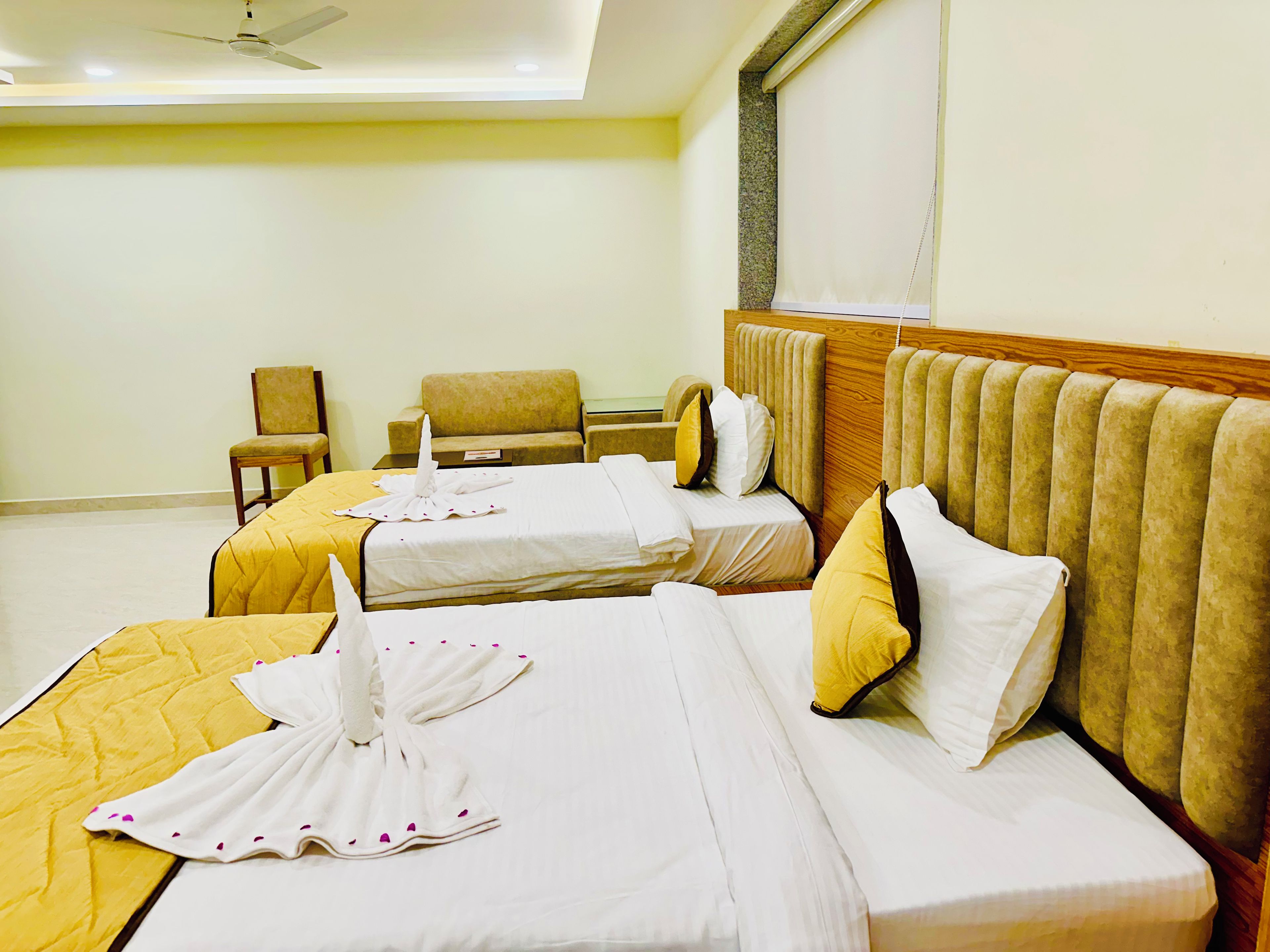 Habitación de hotel con dos camas, una silla y una pequeña mesa.