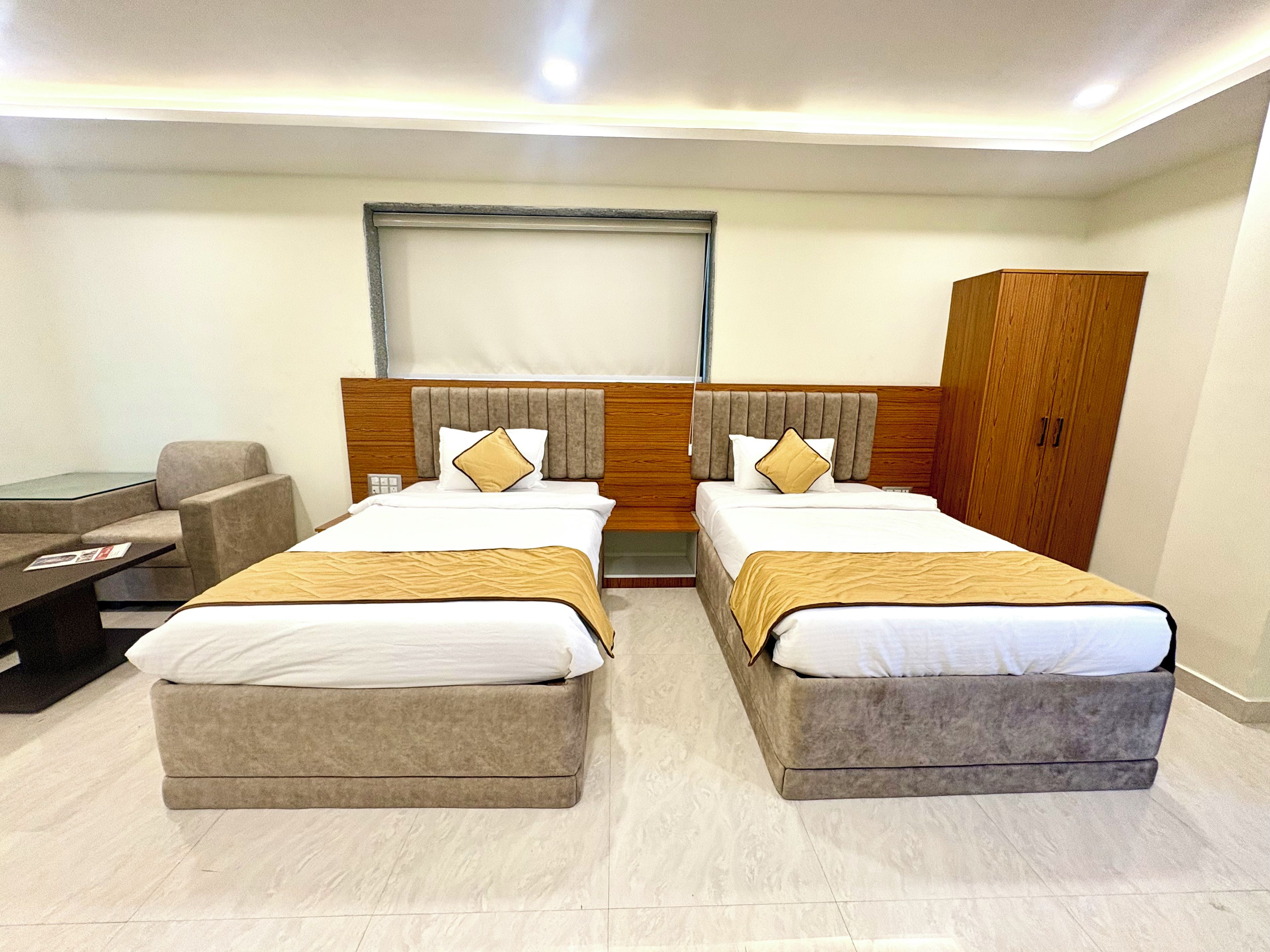 Habitación de hotel con dos camas, un escritorio, una silla y un armario.