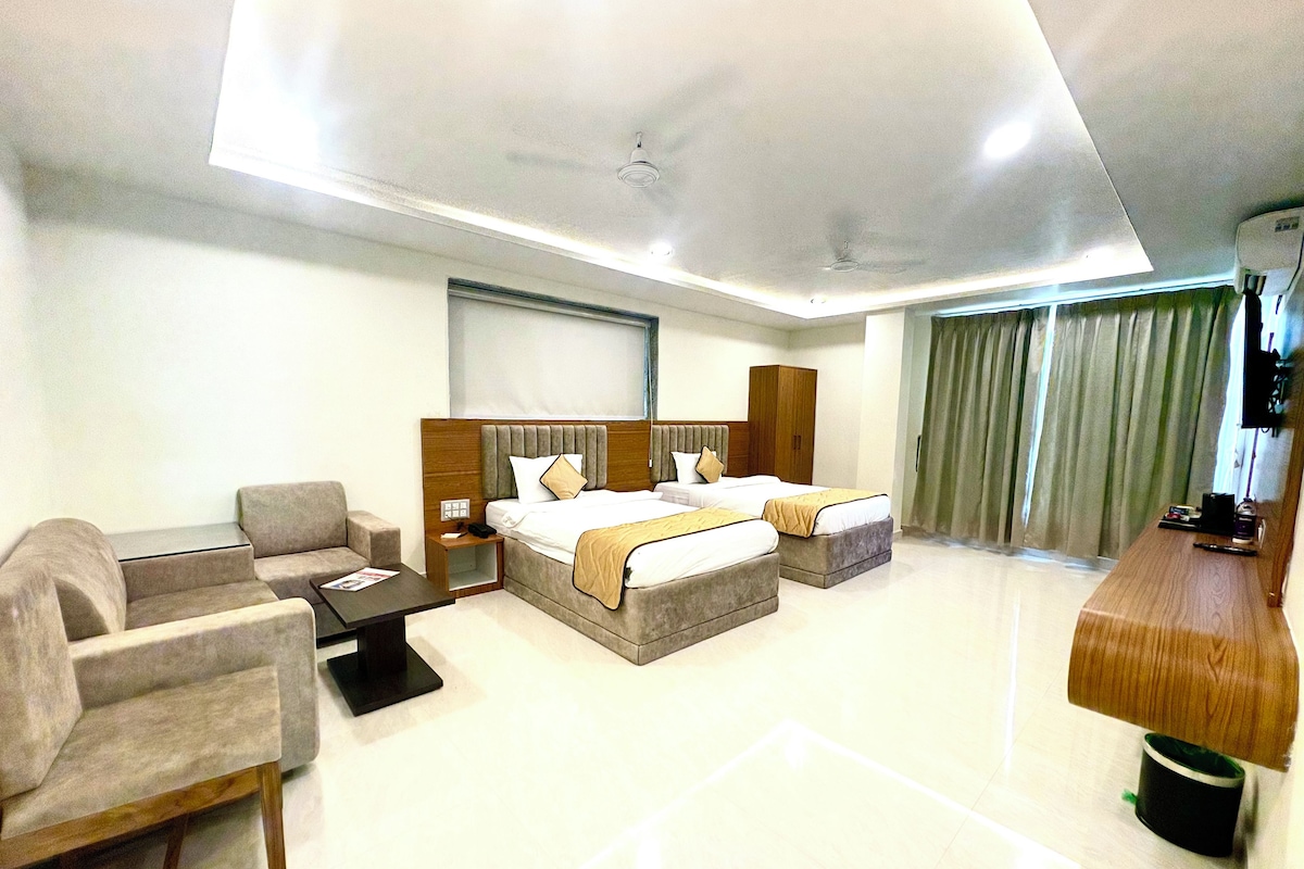 A hotel room with a bed, a sofa, a desk, and a television.