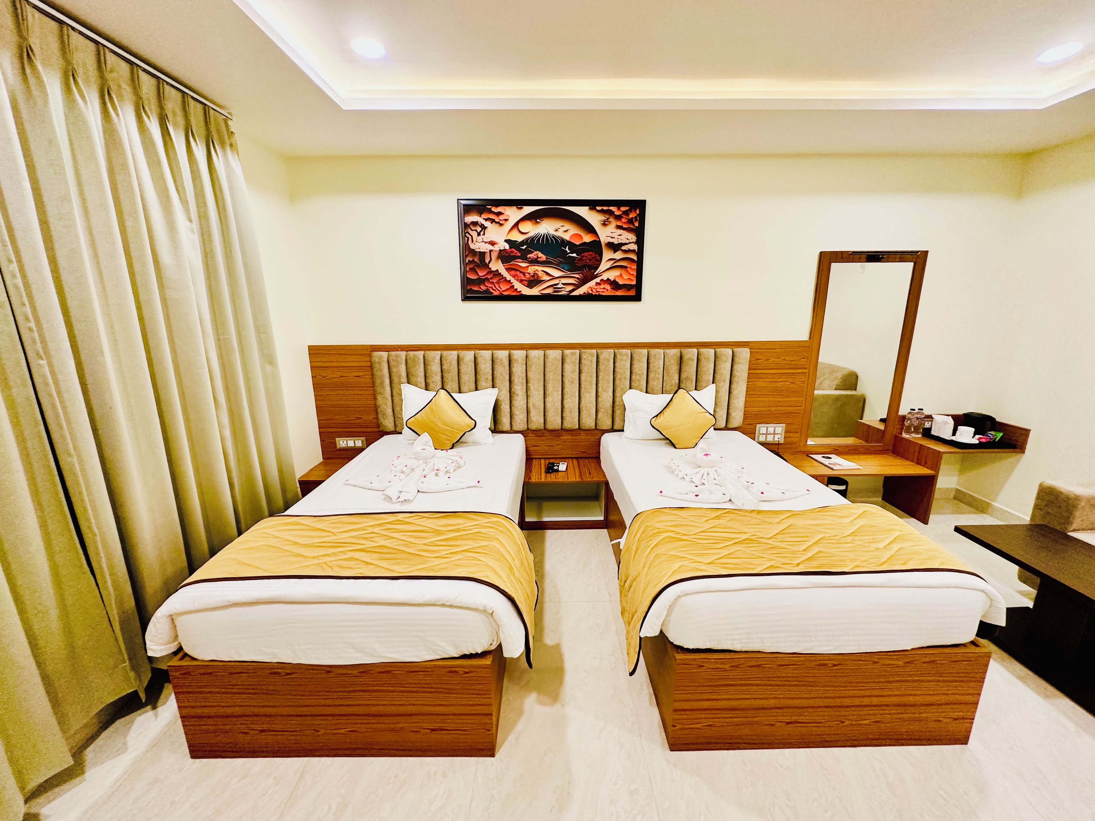 A hotel room with two beds, a headboard, a painting, a desk, and a mirror.