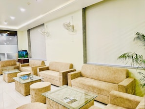 A modern waiting area with beige sofas, glass-top tables, and a large aquarium.