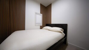 A bedroom with a bed, a window, and a wall with vertical wooden slats.