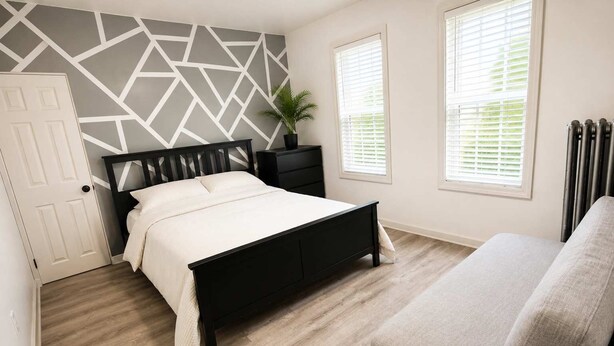 A bedroom with a bed, bedside tables, a potted plant, and a radiator.