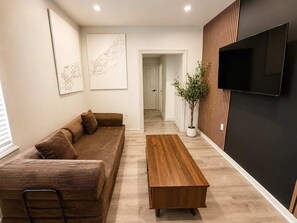 A modern living room with a sofa, a coffee table, and a TV mounted on the wall.