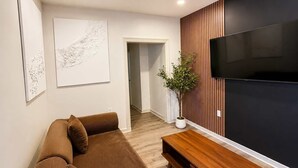 A modern living room with a sectional sofa, a wooden coffee table, a flat-screen TV, and a potted plant.