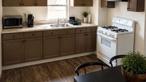 A modern kitchen with wooden cabinets, a stove, a microwave, and a dining table with chairs.