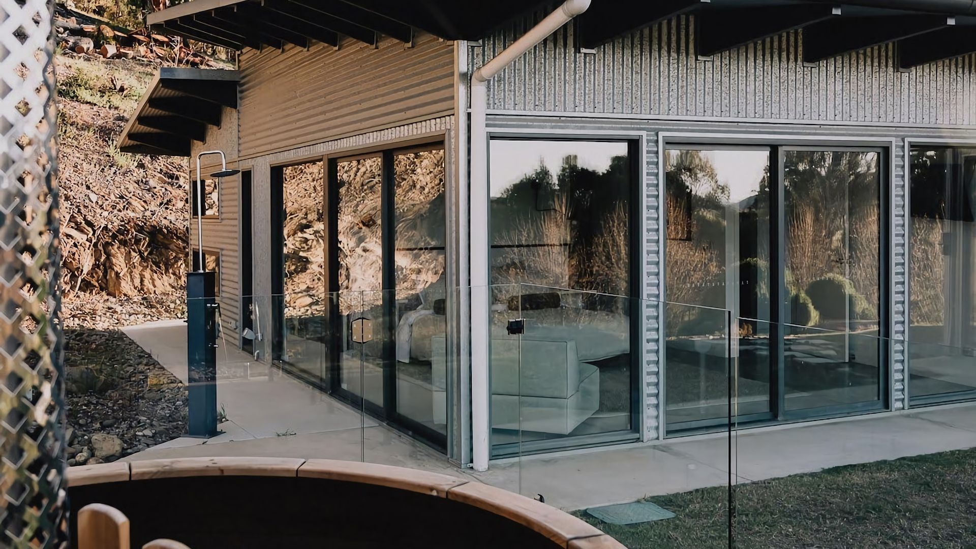 Et moderne hus med store glasvinduer, en stenvæg og en terrasse.