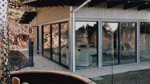 Une maison moderne dotée de grandes baies vitrées, d’un mur en pierre et d’un espace patio.