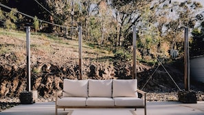 A modern outdoor seating area with a cushioned bench, surrounded by natural landscape and trees. - Echo 1 Bedroom - couples retreat (Buffalo River)
