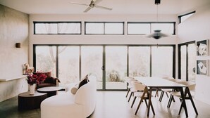 Ein modernes Interieur mit Essbereich, weißen Möbeln und großen Fenstern.