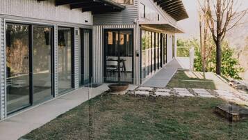 A modern house with large glass doors, a stone pathway, and a small garden area.