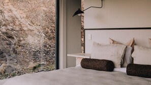 Une chambre avec un mur en pierre, un lit avec des oreillers et une lampe de chevet.