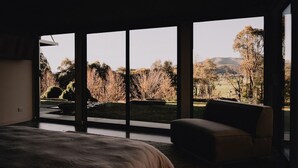 Ein Schlafzimmer mit großem Fenster, einem Bett und einem Sessel.