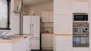 Eine moderne Küche mit weißen Schränken, einer Edelstahl-Dunstabzugshaube, einer Mikrowelle und einem Backofen.