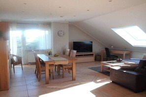 Ein geräumiger Wohnbereich mit Esstisch, Sofa und Fernseher.